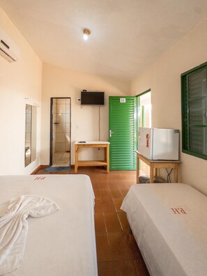 Habitación de hotel con dos camas, un televisor, una puerta verde y una mesita.