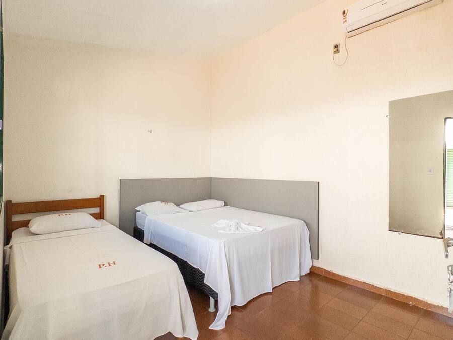 Una habitación con dos camas individuales, un espejo grande y un equipo de aire acondicionado en la pared.