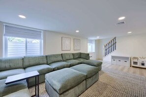 A modern living room with a sectional sofa, a small table, and a staircase leading to an upper level.