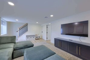Una sala de estar moderna con un televisor de pantalla plana, un sofá y una escalera.