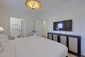 A hotel room with a bed, a television mounted on the wall, and a door leading to a bathroom.