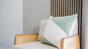 Un coin de pièce avec un fauteuil en osier, un coussin et un mur fait de lattes de bois.
