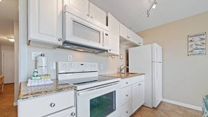 A kitchen with white cabinets, a built-in oven, a microwave, and a refrigerator. - Flash Sale. Direct Gulf Front 1/1 Sleeps 6 (Gulf Shores)