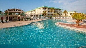 A swimming pool with lounge chairs and a building with a green roof in the background. - Flash Sale. Direct Gulf Front 1/1 Sleeps 6 (Gulf Shores)