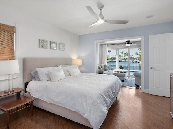 A bedroom with a large bed, a ceiling fan, a nightstand, and a view of a pool and outdoor seating area. - Waterfront 3BR/2BA Marco Island home with heated pool, WiFi, and kitchen. (Marco Island)