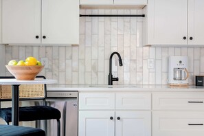 Een moderne keuken met witte kasten, een zwarte kraan en een koffiezetapparaat.