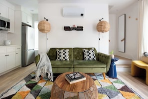 Una sala de estar moderna con un sofá verde, una mesa de centro y una alfombra estampada.