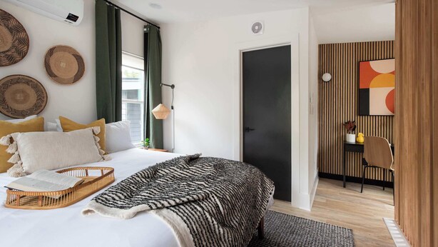 Une chambre à coucher moderne avec un lit, une table de chevet et une vue sur l’extérieur.