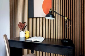 Un escritorio con un libro, una lámpara y objetos decorativos frente a una pared de madera con listones verticales.