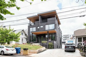 Une maison moderne à deux étages, dotée d’un balcon, d’un garage et d’une allée.
