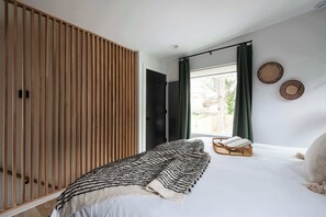 Une chambre à coucher comprenant un lit, une armoire en bois, une fenêtre avec des rideaux et deux éléments de décoration murale.
