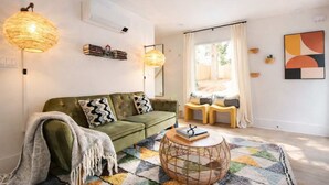 Un salon chaleureux avec un canapé vert, un tapis à motifs et une table basse en osier.