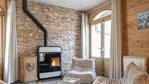 A cozy living room with a stone wall, a fireplace, and comfortable seating.
