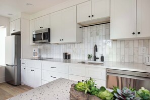 Una cocina moderna con armarios blancos, electrodomésticos de acero inoxidable y salpicadero de mármol.