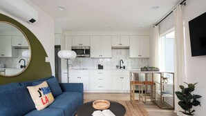 A modern living room with a blue sofa, a round coffee table with an open book, and a large mirror on the wall. - Caviar Dreams (Atlanta)