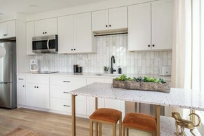 A modern kitchen with white cabinets, stainless steel appliances, and a marble backsplash.