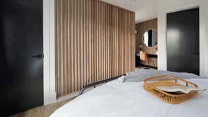 A modern bedroom with a bed, a wooden slatted wall, a round mirror, and a black door. - Caviar Dreams (Atlanta)