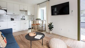 A modern kitchen with white cabinets, a black countertop, and a dining area with stools.
