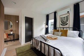 A modern bedroom with a bed, bedside table, and a wall-mounted air conditioner.