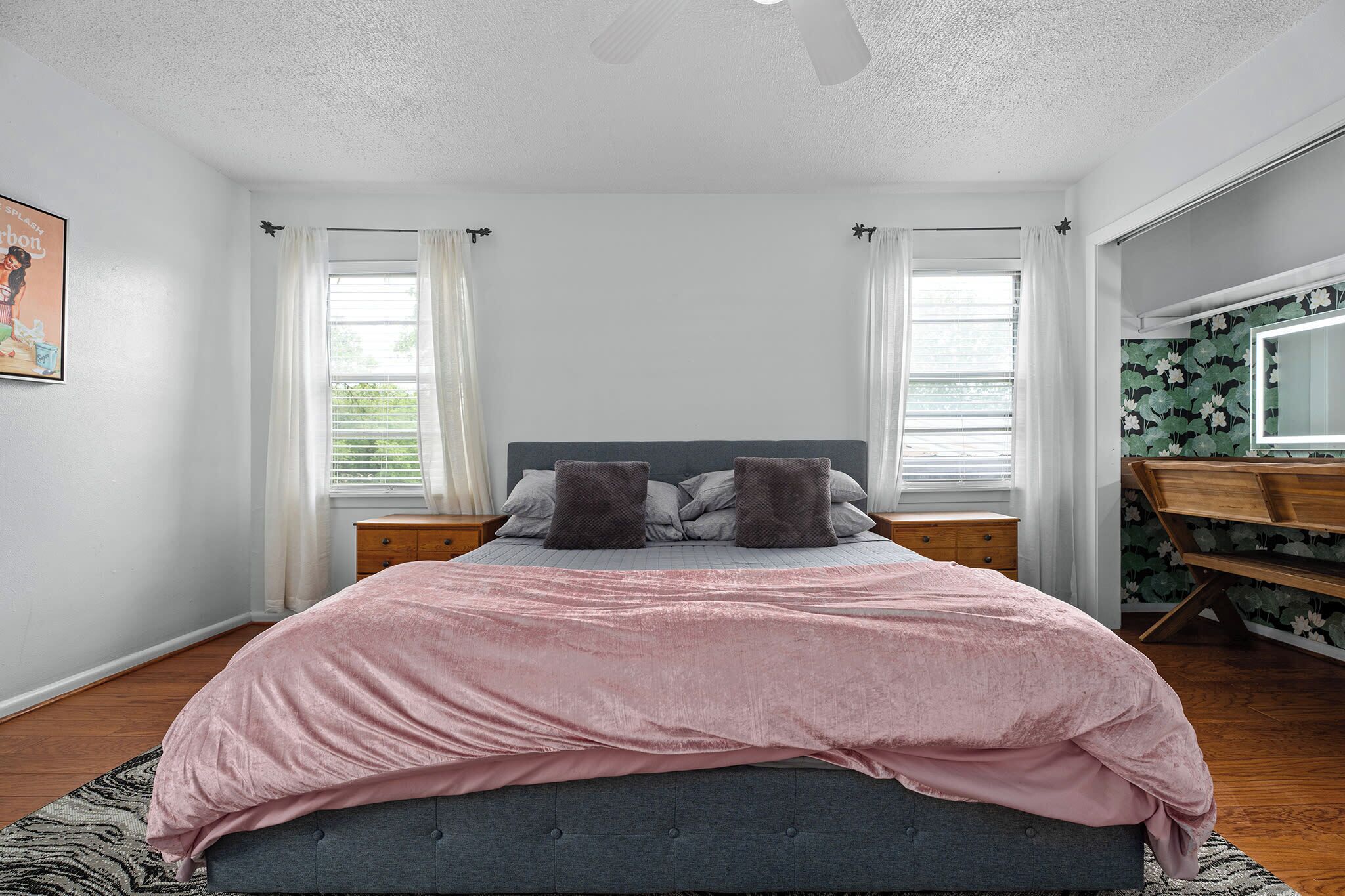 Une chambre à coucher comprenant un lit, deux tables de chevet, un bureau et un ventilateur de plafond.