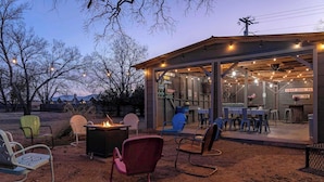 Ein rustikaler Außenbereich mit Stühlen und einem Feuerkorb, eine überdachte Terrasse mit Tischen und Stühlen sowie ein Schild mit der Aufschrift 'GRAY DOG FARMS'.