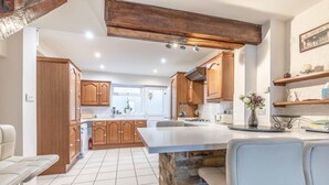 A modern kitchen with wooden cabinets, a central island, and a stone accent wall.