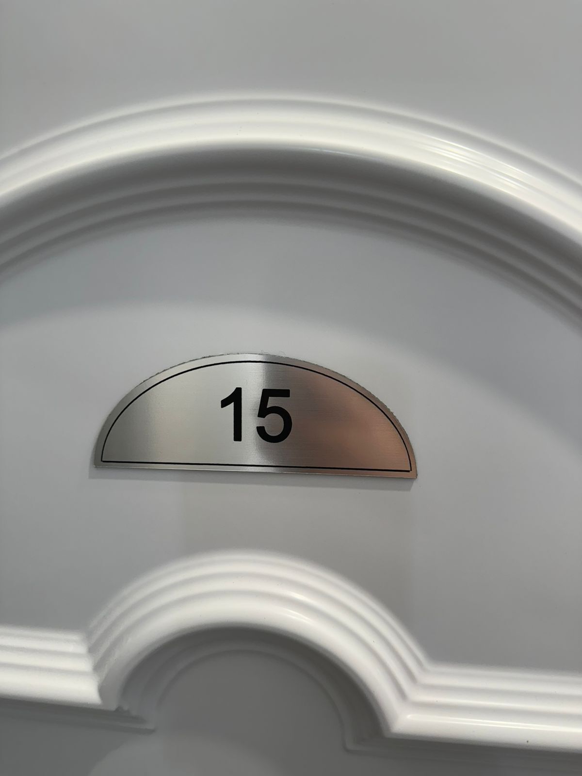 A door with a metallic number plate displaying the number 15.