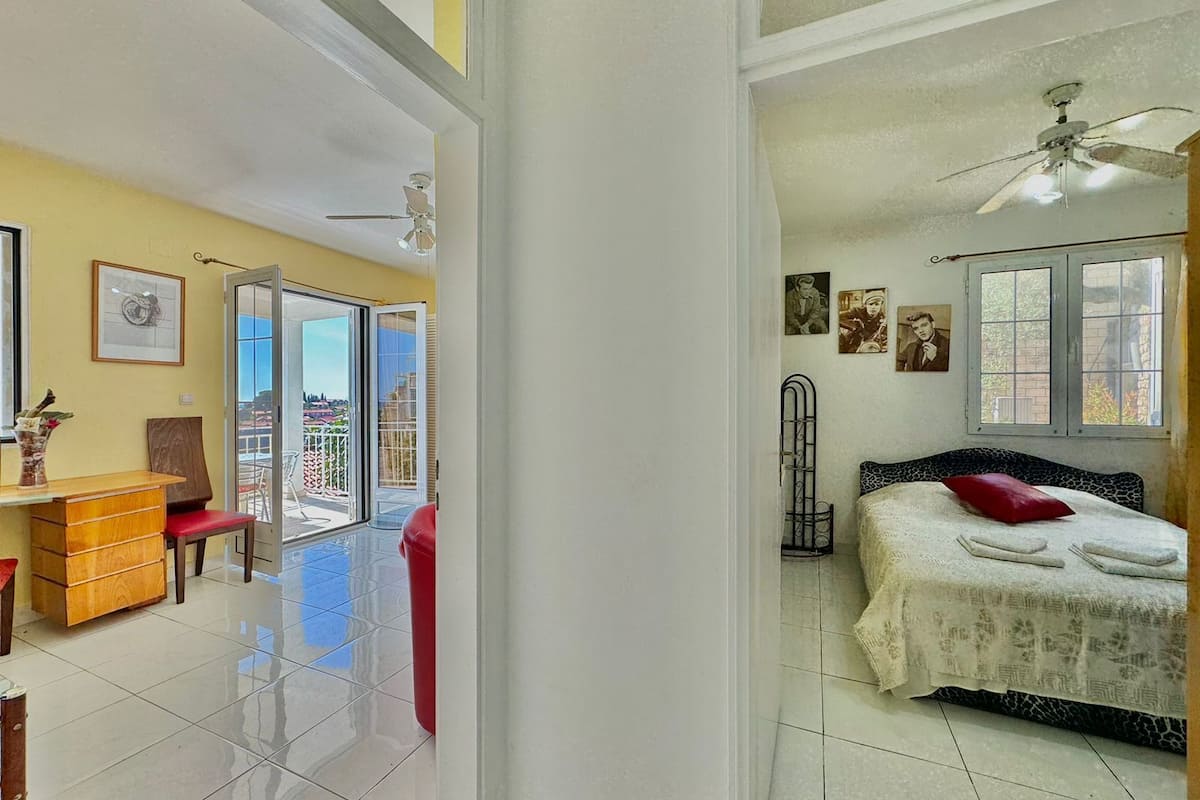 A bedroom with a bed, a ceiling fan, and a window.