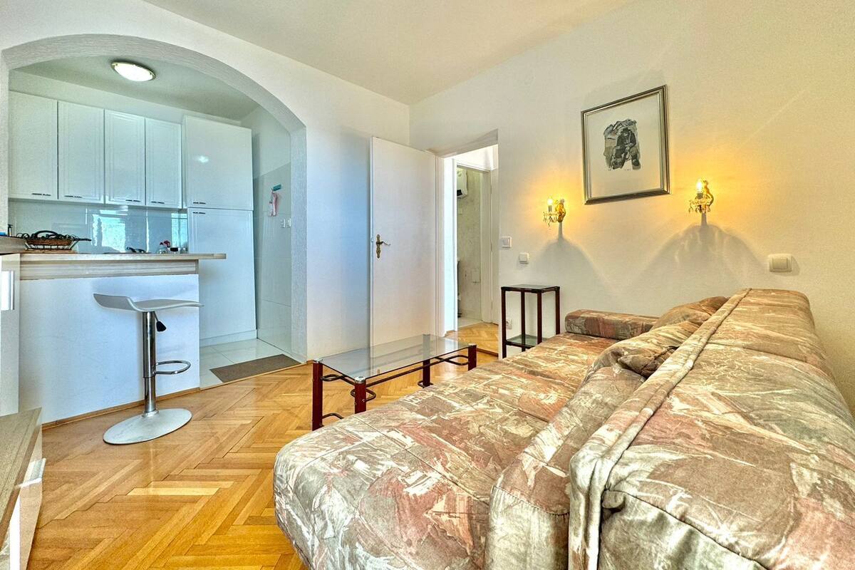 A bedroom with a bed, a desk, and a kitchenette.