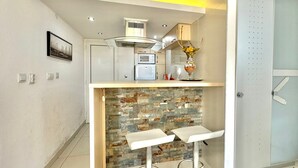 A compact kitchen with a built-in island, a microwave, and a refrigerator. - Sun Rose apartments Sveti Stefan (Sveti Stefan)