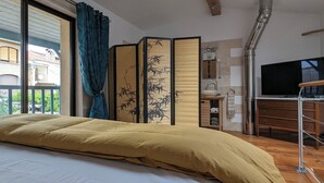 Un dormitorio con una cama grande, un aparador de madera, un televisor y un shoji corredizo con motivos de bambú.
