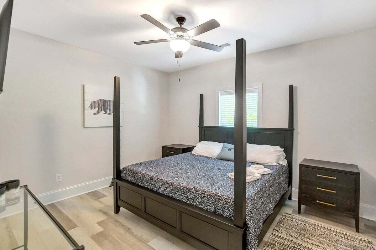 Uma cama com dossel, um abajur e um quadro na parede.