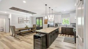 A modern kitchen with a central island, pendant lighting, and a dining area with a bench and chairs. - Jocassee Retreat - .5 miles from Lake Jocassee (Salem)