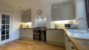 A modern kitchen with wooden flooring, a gas stove, built-in oven, microwave, and sink. - Fell View - sleeps 4 guests  in 2 bedrooms (Portinscale)