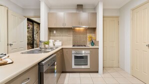 Une cuisine moderne avec des armoires de couleur beige, une hotte de cuisinière en acier inoxydable, un four encastré et un lave-vaisselle.
