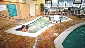 An indoor swimming pool with stone flooring, a pool ladder, and a view of a building outside. - 2 bedroom oceanfront condo with free WiFi, 2 pools and much more in this uptown location with a great view and steps from beach! (Ocean City)