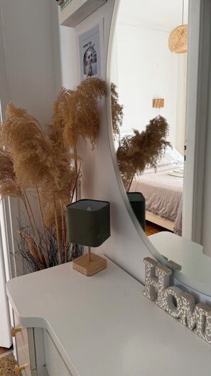 Une chambre moderne avec une coiffeuse blanche, un miroir et des décorations à base de plumes d’herbe de la pampa.