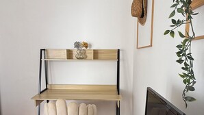 En arbetsplats med ett skrivbord i trä, en bekväm stol, en tv och en växt.