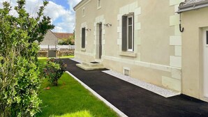 Un bâtiment à deux étages doté d’une façade symétrique, d’une entrée centrale avec des marches et d’un petit jardin agrémenté d’un chemin pavé.