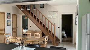 Une cuisine spacieuse avec un escalier en bois, un coin repas avec une table ronde et un réfrigérateur.