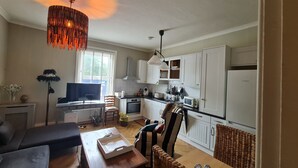 A compact living space with a kitchenette, a dining area, and a seating area with a TV and decorative items. - Beautifully Decorated 1-bed Apartment in Sale (Sale)