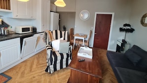 A compact living space with a kitchenette, a dining area, and a seating area with a sofa and armchair. - Beautifully Decorated 1-bed Apartment in Sale (Sale)