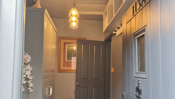 A hallway with a closed door, a bench, a hanging light fixture, and a framed picture on the wall. - Beautifully Decorated 1-bed Apartment in Sale (Sale)