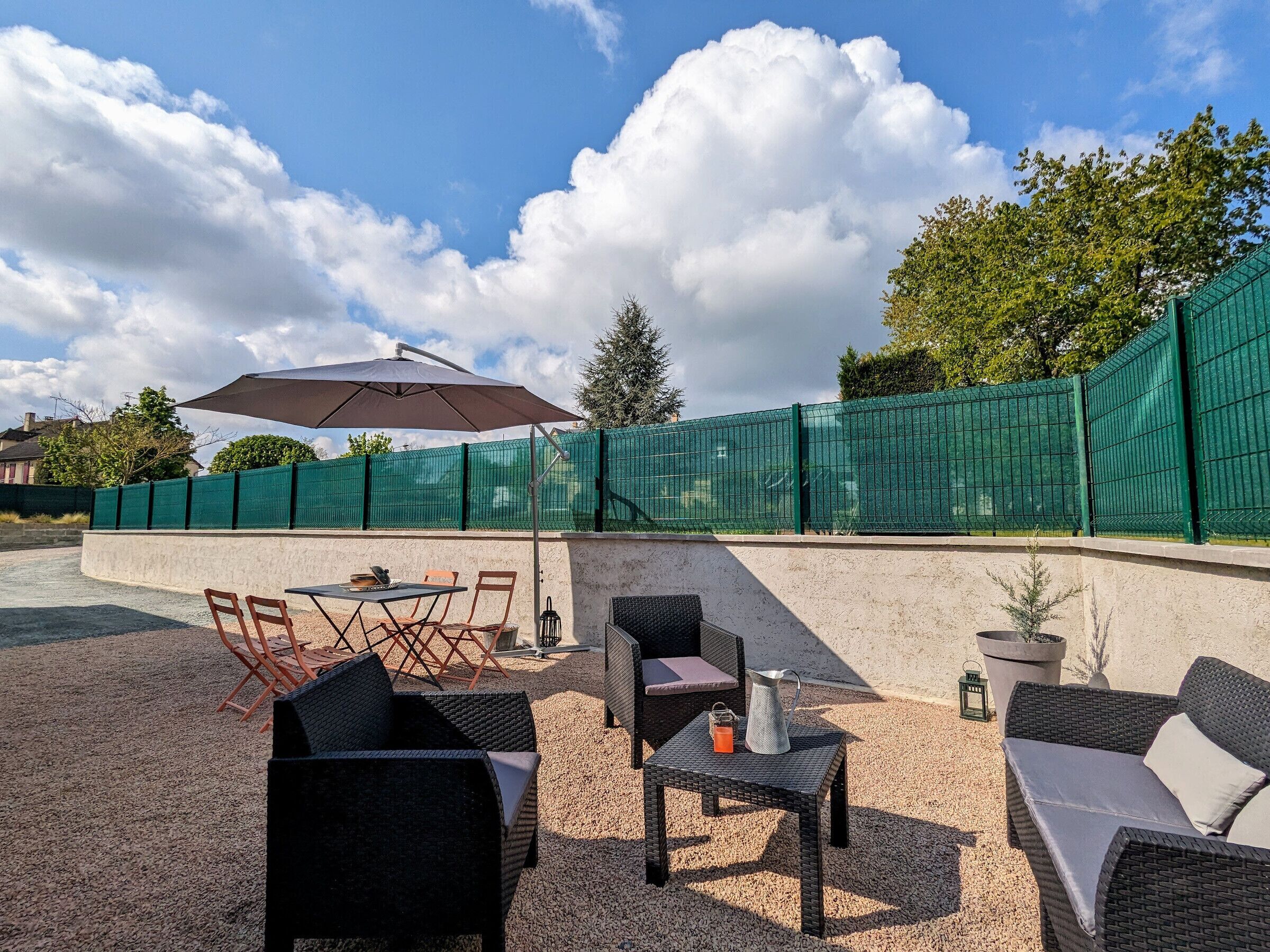 An outdoor patio area with wicker furniture, a table, and an umbrella.