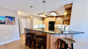 Una cocina moderna con una isla central, armarios de madera e iluminación colgante.