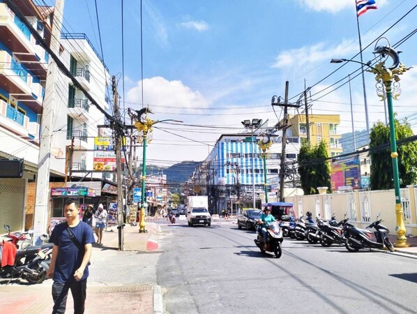 A street with buildings, parked motorcycles, and a few cars. - Minotel Patong (Patong)