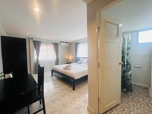 A hotel room with a bed, a desk, and a shower area. - Minotel Patong (Patong)