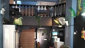 A spacious kitchen with a central island, a dining area with wooden furniture, a staircase leading to an upper level, and a ceiling fan. - Minotel Patong (Patong)