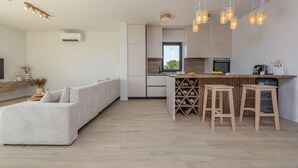 Una cocina moderna con una isla integrada, taburetes de madera y un ventanal grande.