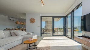 Una sala moderna con sofá, mesa de centro y comedor con sillas y mesa.